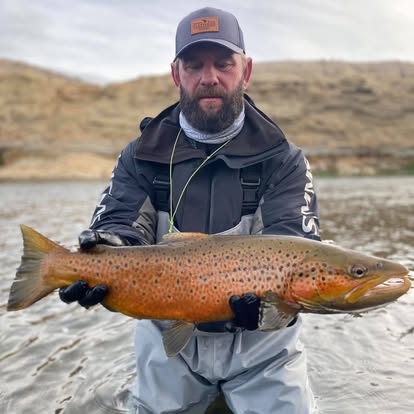 Guide holding a massive golden brown trout